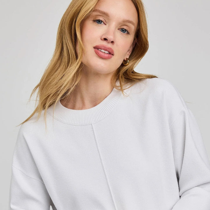 Woman wearing a light gray sweater against a plain background